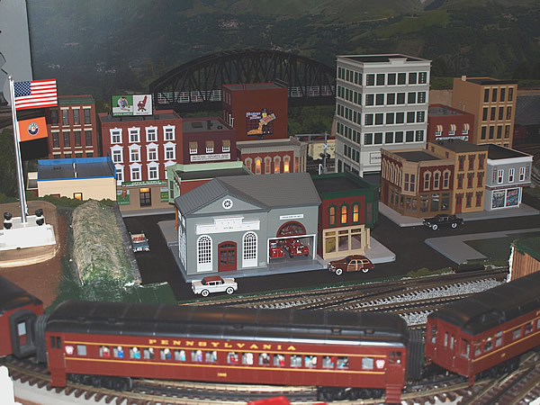 A view of the layout buildings with a passenger train in the foreground.